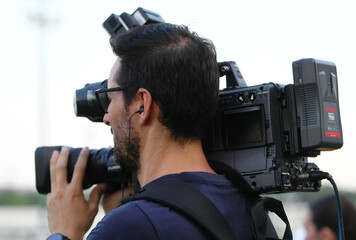 Operador de cámara de televisión profesional filmando una retransmisión en vídeo un reportaje...