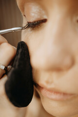 Eyelash extensions. Makeup artist applies eyelashes to model eyes. Close-up vertical view