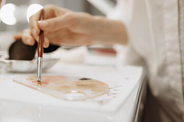 Makeup artist, makeup, brush paint concept. Makeup artist dips brush into paint. Close-up