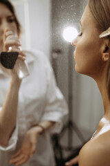 Makeup artist spraying makeup on model. Close-up vertical