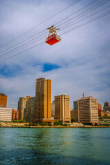 New York City skyline and Upper East Side buildings with a cable car in the air, as seen from Roosevelt Island over the East River, USA