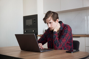 a young man  concentrate our energy and using a laptop, connecting to the Internet in the kitchen...