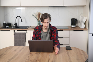 a young man  concentrate our energy and using a laptop, connecting to the Internet in the kitchen...