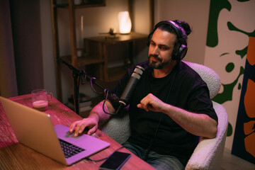 Audio podcast recording studio. A young man sits at a table in front of a microphone, recording the release of an online audio show. The host is recording the show.