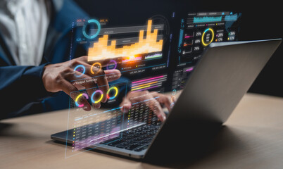 A person interacts with a laptop displaying futuristic transparent data visualizations and charts in a high-tech digital workspace.
