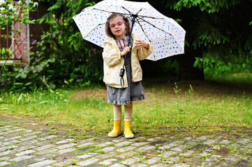 Kid girl with umbrella in yellow boots