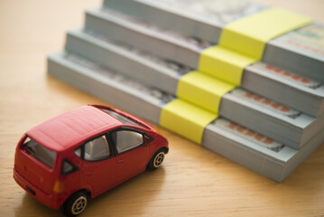 Simple car toy is in front of high stairs stack US dollar banknotes. Money management and financial planning for buying a car,  auto leasing or hire purchase concept.
