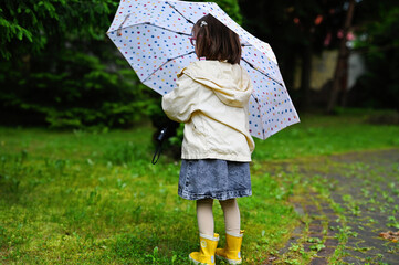 Kid girl with umbrella in yellow boots