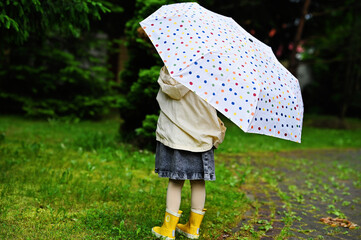 Kid girl with umbrella in yellow boots