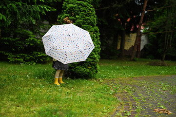Kid girl with umbrella in yellow boots