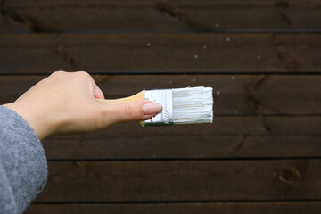 Construction brush with white paint on a wooden background.