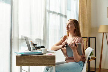 Young woman enjoying a cozy afternoon at home while working on her tablet by the window