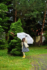 Kid girl with umbrella in yellow boots