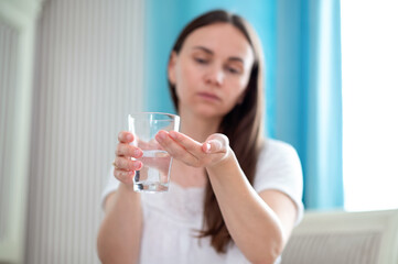 Woman holding glass of water and pill in hand, preparing to take medicine, concept health routine
