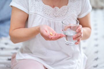 Female hands holding a glass of water and a pill, ready to take medicine, health and self-care...