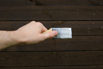 Construction brush with white paint on a wooden background.