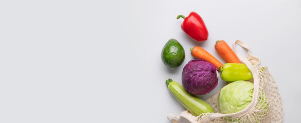 Various healthy organic vegetables in natural textile eco-friendly wicker string bag on gray background flat lay top view. Healthy food, seasonal products. Zero waste bag