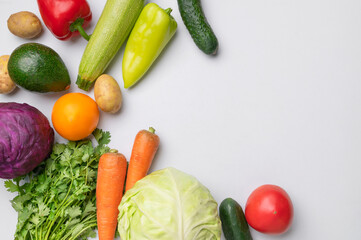 Various fresh vegetables: cabbage, tomato, cucumber, avocado, bell pepper, zucchini, cilantro, carrot, potato on gray background, flat lay top view. Healthy food concept, seasonal products