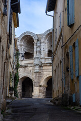 Ancient roman amphitheatre of Arles seen through a narrow street