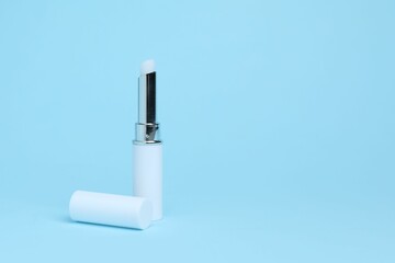 One white lipstick on light blue background, space for text
