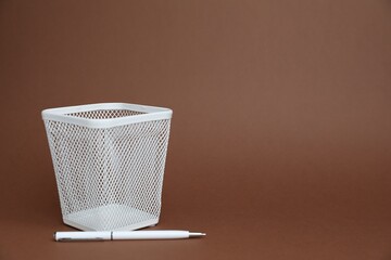 White pen and holder on brown background, space for text