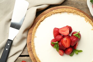 Tasty cheesecake with strawberries, mint and server on wooden table, flat lay