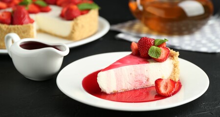 Piece of tasty cheesecake with strawberries, sauce and mint on black table, closeup
