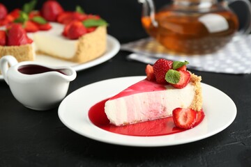 Piece of tasty cheesecake with strawberries, sauce and mint on black table, closeup