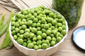 Fresh green peas in bowl, jar and pods on wooden table, closeup. Pickling vegetables