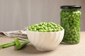 Fresh green peas in bowl, jar and pods on wooden table, closeup. Pickling vegetables