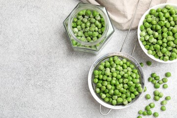 Fresh green peas and pickling jar on light grey table, flat lay. Space for text
