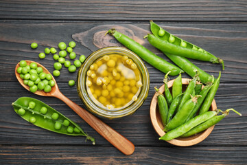 Pickled peas in jar and pods on black wooden table, flat lay