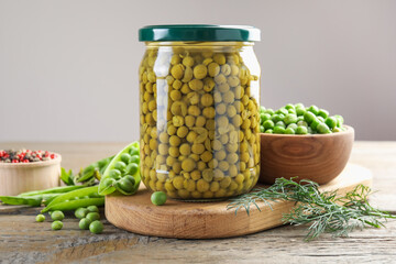 Pickled peas in jar, spices, dill and pods on wooden table, closeup