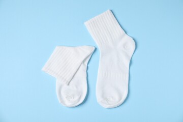 Pair of comfortable white socks on light blue background, top view