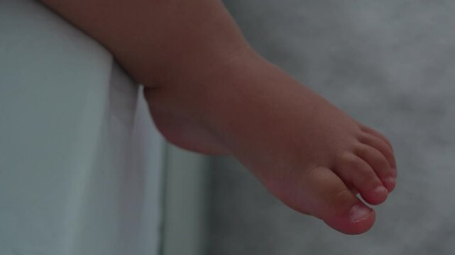 A tiny child's foot wiggles the toes of the left leg.
An extremely close-up shot.