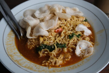 A savory plate of Indonesian bakmi noodles served with vegetables, sauce, and topped with crunchy...