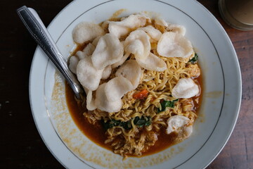 A savory plate of Indonesian bakmi noodles served with vegetables, sauce, and topped with crunchy...