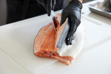 Chef slicing a big salmon meat in the kitchen