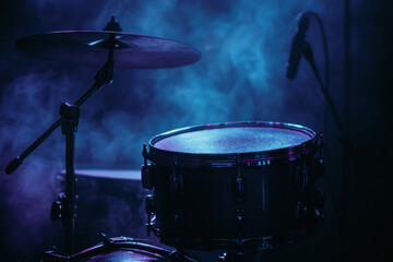 Dramatic blue stage lighting highlights snare drum and cymbal set with microphone surrounded by atmospheric smoke during live performance