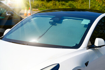 Protective reflective matte surface under the windshield of the passenger car parked on a hot day,...