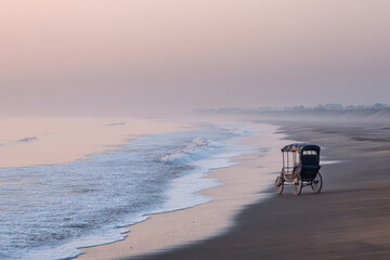 serene scene of rickshaw on sandy beach with gentle waves lapping at shore