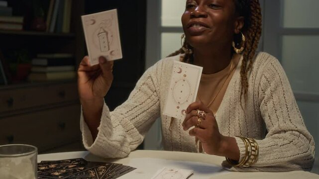 African American tarot reader looking at cards, showing them to unrecognizable female client and asking to pick another one