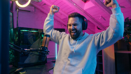 Happy young man Caucasian guy male celebrating victory gaming on computer stream with headphones...