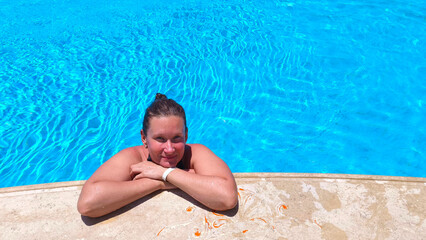young woman relaxing in blue water of hotel swimming pool. Summer Vacation and Travel