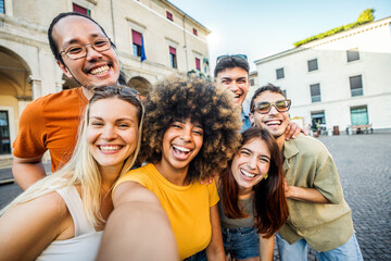 Multicultural cheerful friends taking selfie pic with smart mobile phone device - Youth community people laughing at camera together - Friendship concept with guys and girls having fun outdoors