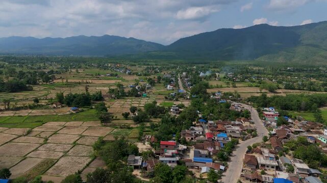 Wide aerial perspective of rural farming community in Nepal, flat agricultural fields preparing for plantation in Terai region with cloudy horizon