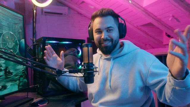 Caucasian smiling talking microphone at camera guy male gamer man streamer influencer blogger in headphones record channel online vlog chat talk e-sport video game cyber sport addict radio presenter