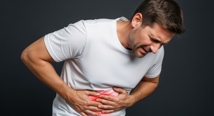 Young Man Suffering From Severe Abdominal Pain Holding Stomach Against Dark Background