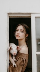 A woman is holding a pig in front of a window