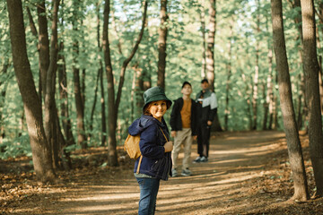 Fototapeta premium Cute little kid girl go hiking trip with backpacks at mountain forest with family. Explorer and adventure concept.